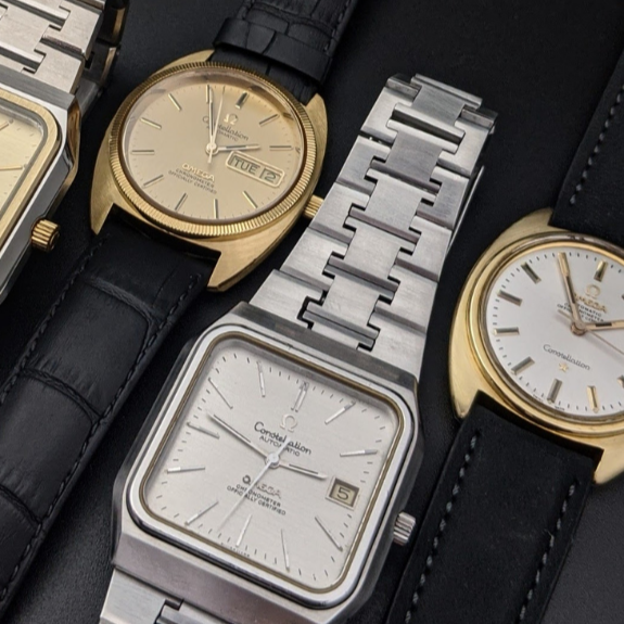 Kolekcja czterech zegarków vintage Omega Constellation. Dwa modele w złotych kopertach na czarnych paskach i dwa modele w srebrnych kopertach, jeden na bransolecie, drugi na pasku.