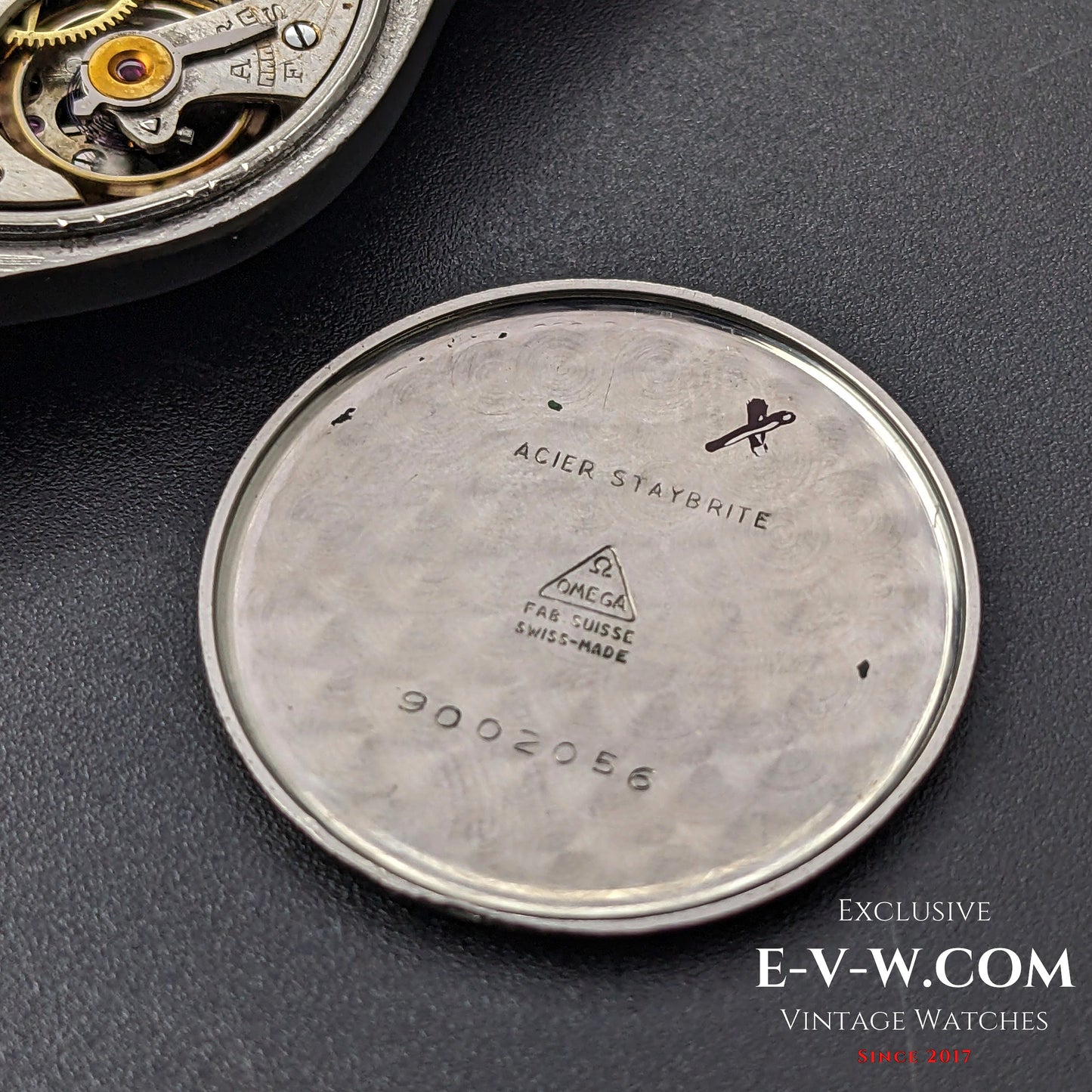 Inside case back of the Omega wristwatch, engraved with 'Acier Staybrite' and serial numbers, confirming its authenticity as a vintage 1935 model.