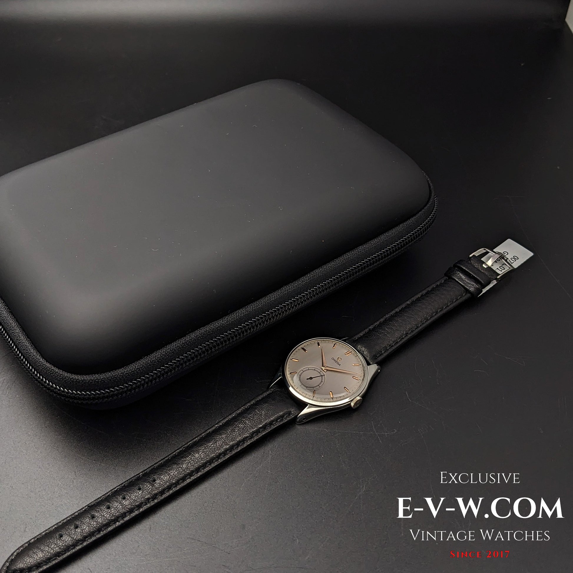 Omega Jumbo 38mm Ref. 2505 20 wristwatch displayed alongside a black protective case, highlighting its vintage elegance and secure storage.