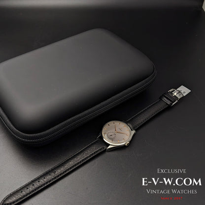 Omega Jumbo 38mm Ref. 2505 20 wristwatch displayed alongside a black protective case, highlighting its vintage elegance and secure storage.