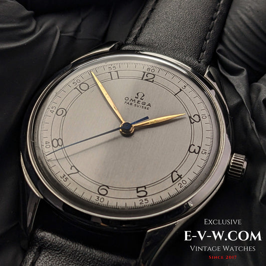 77-year-old vintage Omega Sector Jumbo wristwatch, 38mm Ref. 2506 1, featuring a silver dial with gold-tone hands and a black leather strap.