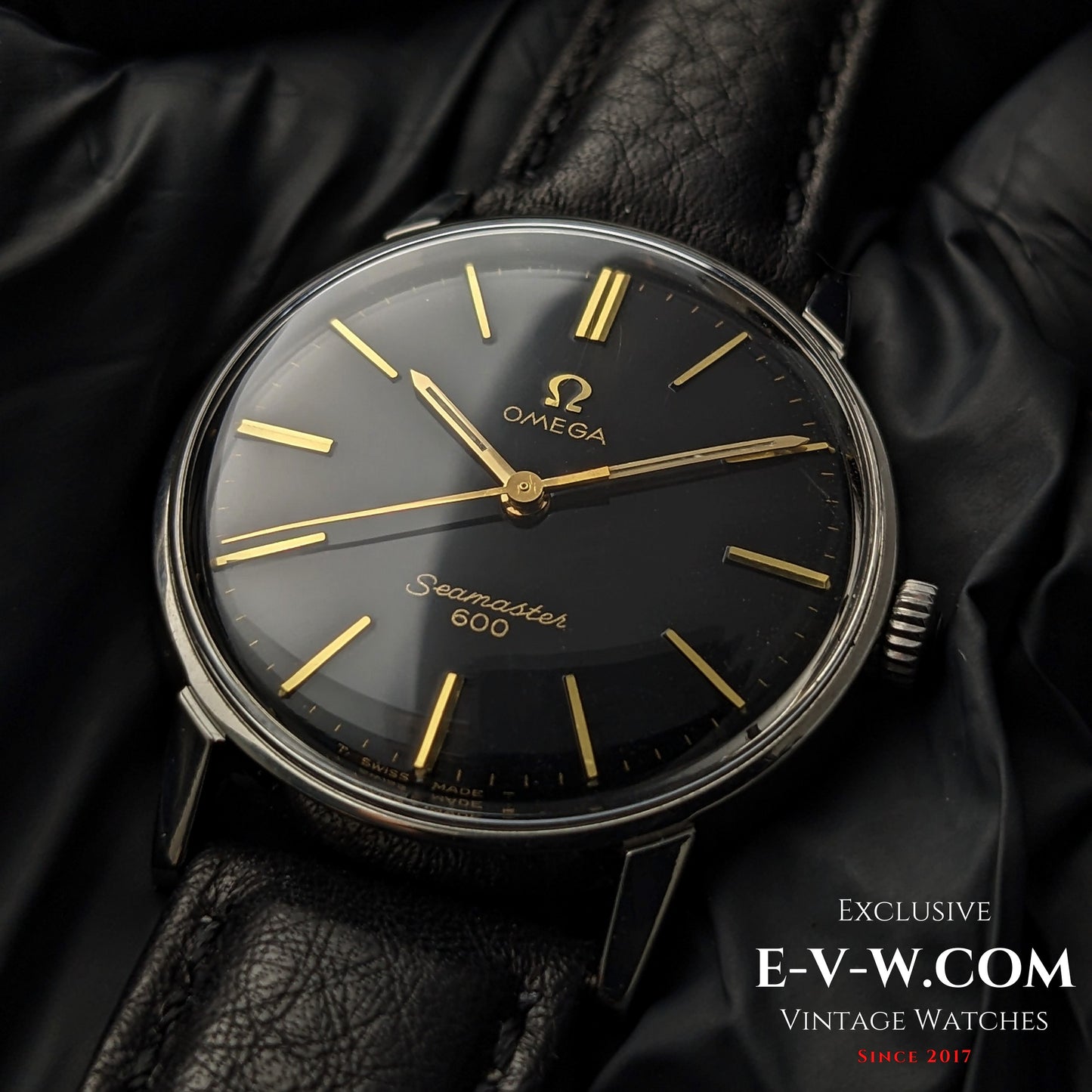 Vintage Omega Seamaster 600 1966 Ref. 135011 with black dial and gold indices on black leather strap, displayed on black glove background.