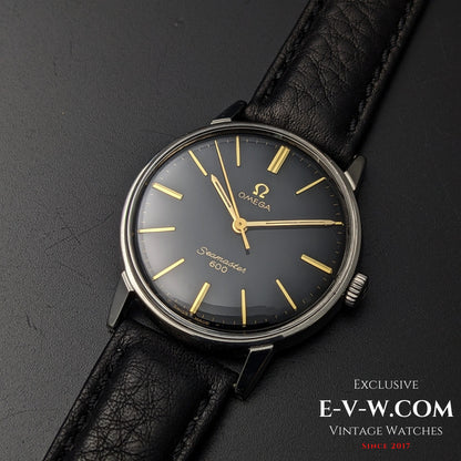 Front view of 1966 Omega Seamaster 600 Ref. 135011 with black dial and gold markers, paired with a black leather strap on dark background.