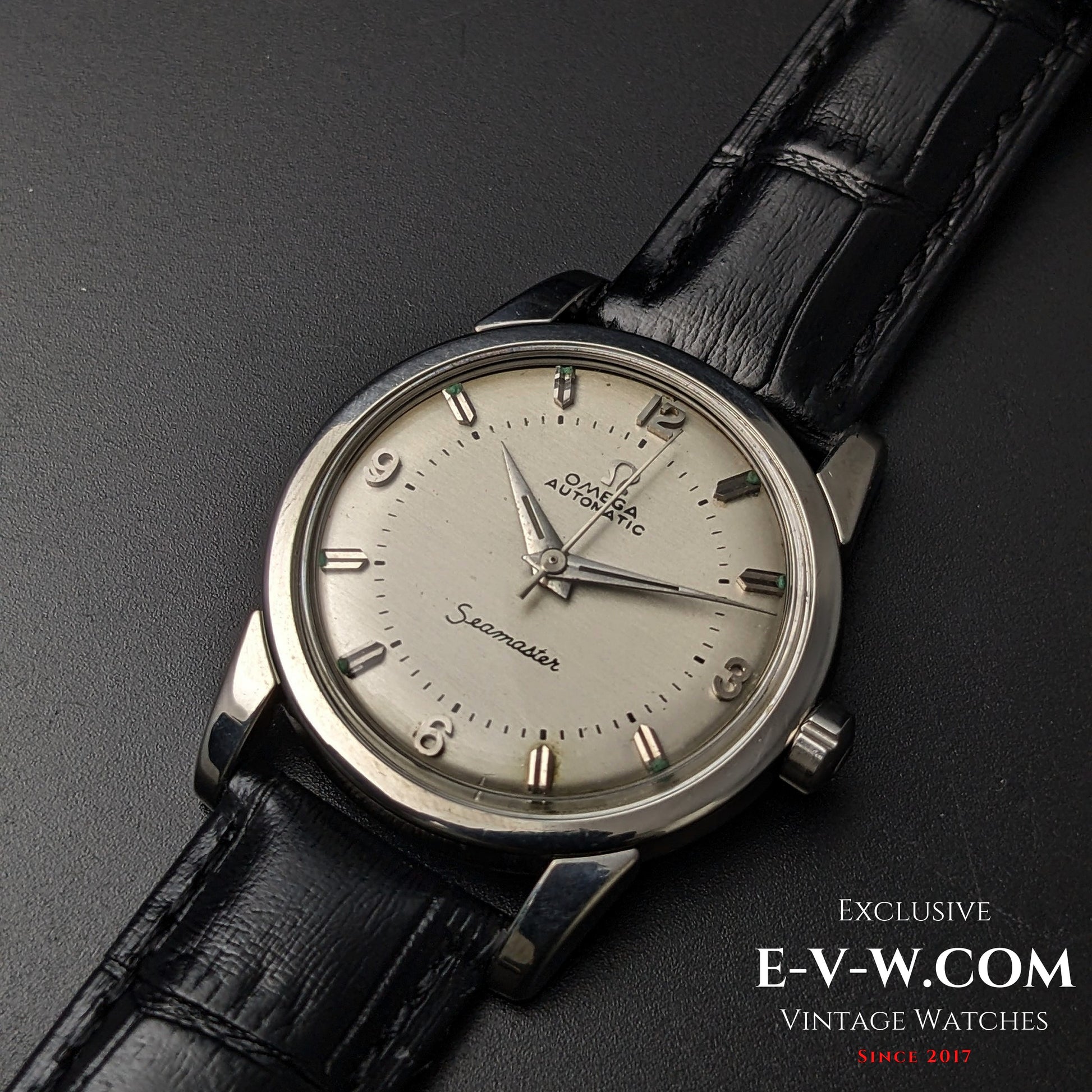 Close-up of Vintage 1958 Omega Seamaster Automatic Watch featuring a silver dial, Arabic numerals, and black leather strap.