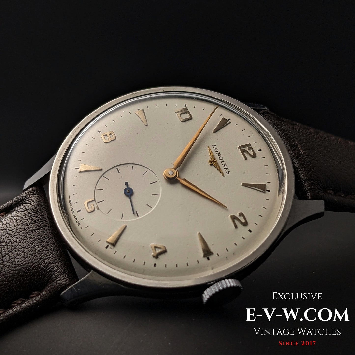 1955 Longines Jumbo Calatrava Ref 2849 with silver dial and gold indices, displayed on brown leather strap against black background.