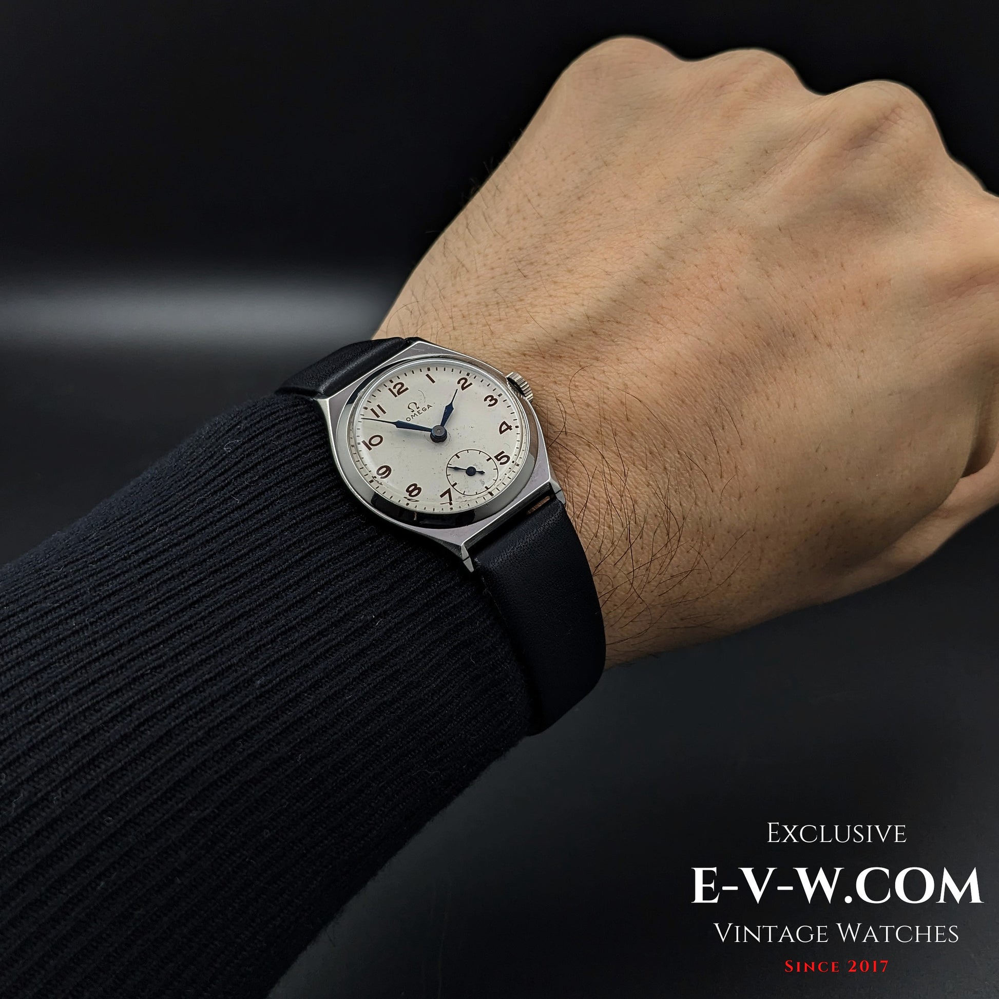 Omega Art Deco wristwatch from 1935 worn on wrist, emphasizing its timeless design with a silver dial, blue hands, and black leather strap.