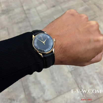 Wrist shot of Vintage Omega WWII Gold Watch 1944 with black dial and gold case, perfect for showcasing timeless military-era elegance.