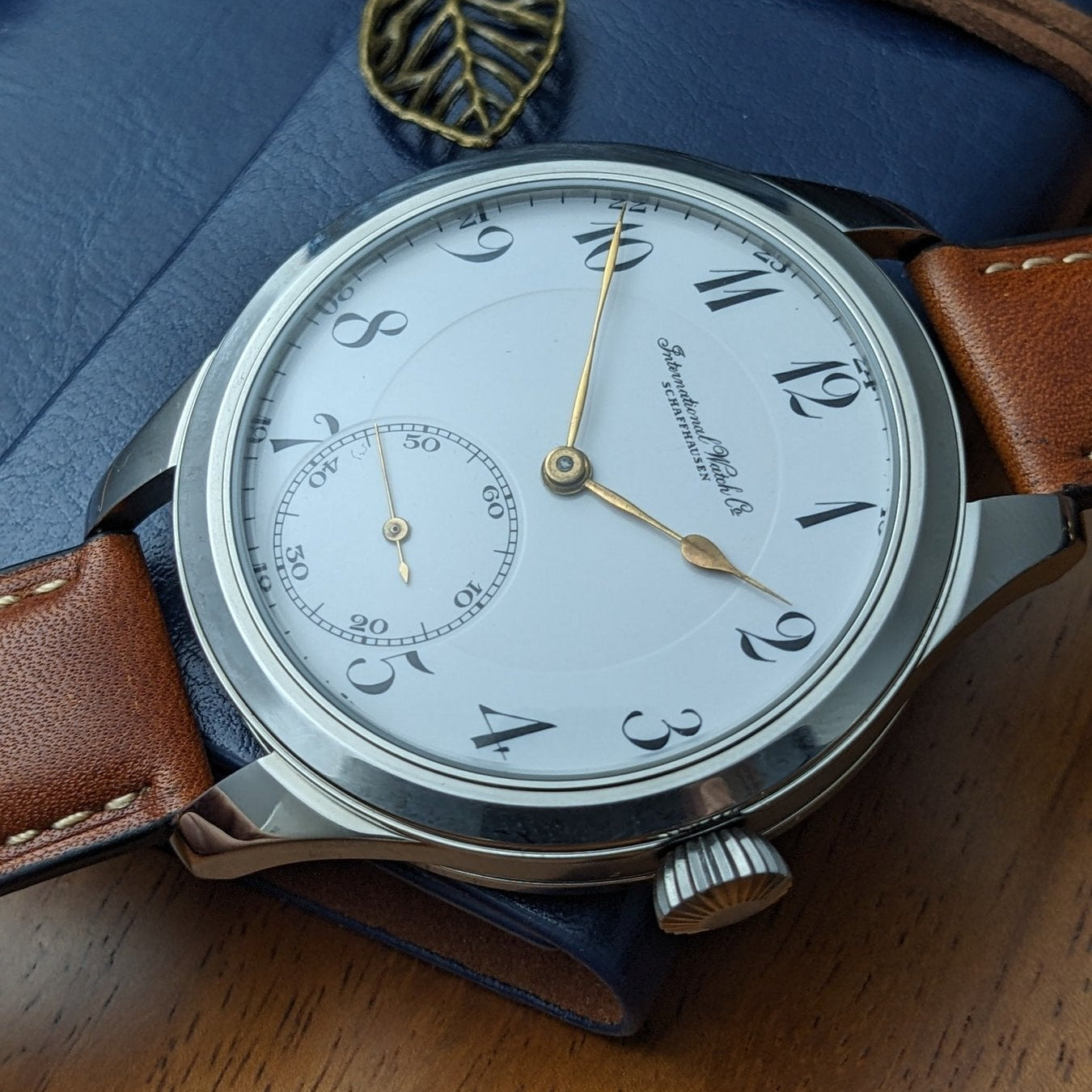 Vintage wristwatch with brown leather strap on a blue textured background